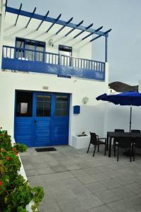 un patio con puerta azul, mesa y sombrilla en Casa Leyna, en El Golfo