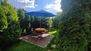 a table and chairs with an umbrella in a garden at Apartamenty Tuwima in Piechowice