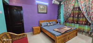 sypialnia z łóżkiem i fioletową ścianą w obiekcie UDUPI HOMESTAY - Garden Villa 5BHK w mieście Udupi