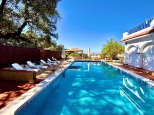 a swimming pool with chairs and a house at Casa 3 habitaciones y Piscina de temporada compartida - - Jacuzzi Spa No incluido -- By TrassierraRooms in Córdoba