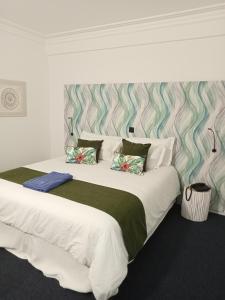 ein Schlafzimmer mit einem großen weißen Bett und einer gestreiften Wand in der Unterkunft Mediterrâneo Madeira in São Vicente