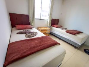 two beds sitting in a room with a window at Apartamento Aconchegante em Paulo Afonso in Paulo Afonso