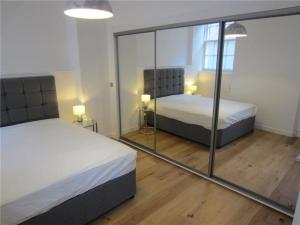 a bedroom with two beds and a mirror at Stylish City Apartment in Edinburgh