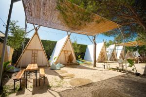 un groupe de tentes dans le sable sous un arbre dans l'établissement Kampaoh Hostel El Palmar, à El Palmar