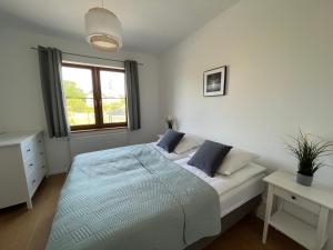 biała sypialnia z łóżkiem i oknem w obiekcie Apartament z ogrodem w Sarbinowie