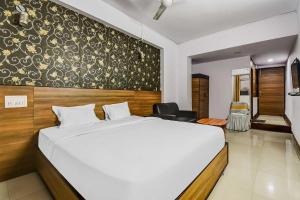 Un dormitorio con una gran cama blanca y una pared en OYO Flagship Hotel Sunset Inn en Gulzārbāgh