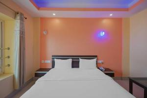 a bedroom with a large white bed with orange walls at Super OYO Kirti Inn in Puri
