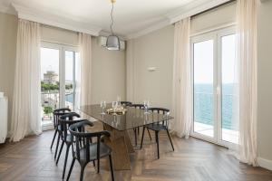 een eetkamer met een tafel en stoelen en grote ramen bij #Primavera: Seafront apt with White tower view in Thessaloniki