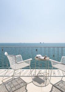 een patio met stoelen en een tafel en de oceaan bij #Primavera: Seafront apt with White tower view in Thessaloniki