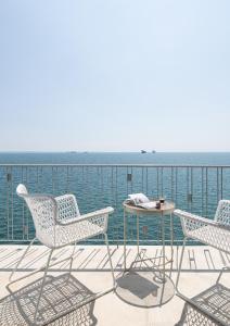 een terras met stoelen en een tafel en de oceaan bij Primavera Seafront apt by halu! next to White Tower in Thessaloniki