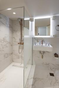 een witte badkamer met een wastafel en een douche bij Primavera Seafront apt by halu! next to White Tower in Thessaloniki