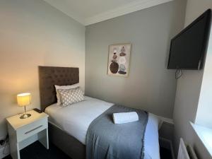 a small bedroom with a bed and a tv at Alexander Hotel Whitley Bay in Whitley Bay