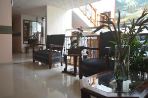 a lobby with chairs and a vase with plants on a table at Hotel Del Parque in La Ceja