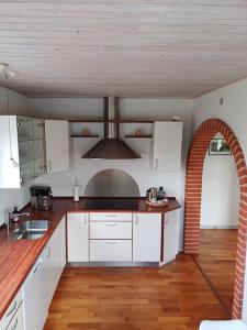 a kitchen with white cabinets and an archway at Bjergby Sønderbo feriehus in Bjergby