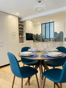 mesa de comedor con sillas azules y cocina en Le Cattleya, studio cosy à Rennes, en Rennes