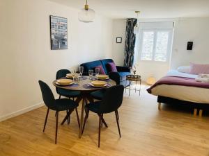 a living room with a table and chairs and a bed at Le Cattleya, studio cosy à Rennes in Rennes