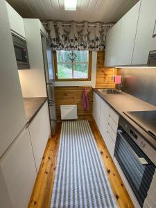 a small kitchen with white cabinets and a striped floor at Cityvilla on the shore of Lake Haapajärvi in Joensuu