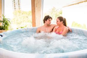 a man and woman sitting in a hot tub at Hotel Lycium Debrecen in Debrecen