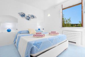 a white bedroom with a bed with pillows on it at Esclusive House [Costa Smeralda Baia Sardinia ] Monica House in Baja Sardinia