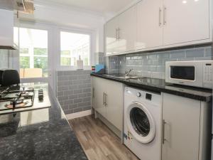 a white kitchen with a washer and a microwave at Coed Bach in Prestatyn