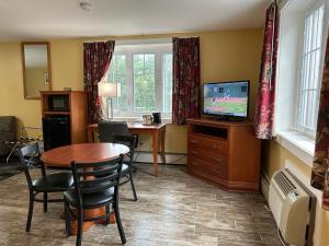 a living room with a table and a television at Swiss Chalets Village Inn in North Conway