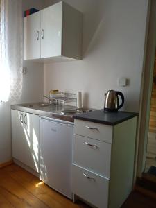 eine Küche mit weißen Schränken und einem Wasserkocher auf der Theke in der Unterkunft Leśniczówka Turowo - Podlasie 