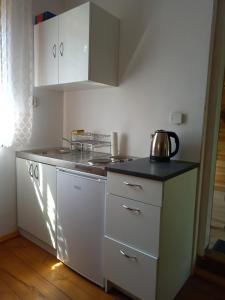a kitchen with white cabinets and a tea kettle on the counter at Leśniczówka Turowo - Podlasie in Nowosiółki
