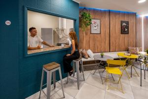 瓦伦西亚SOM Hostel By The Venue的坐在餐厅柜台的男女
