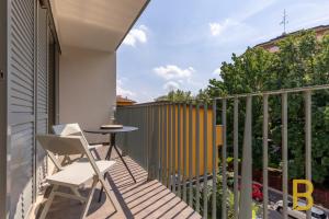 Un balcón con una mesa y una silla sobre una valla en BePlace Apartments at Fondazione Prada, en Milán