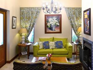 sala de estar con sofá verde y chimenea en Petit Plaisir is a romantic self-catering cottage on the side of the village no1, en Franschhoek