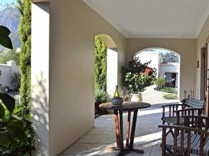 un patio con mesa, sillas y un arco en Petit Plaisir is a romantic self-catering cottage on the side of the village no1, en Franschhoek