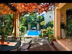 Un patio con mesa y sillas y una piscina. en Petit Plaisir is a romantic self-catering cottage on the side of the village no1, en Franschhoek