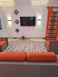 sala de estar con sofá naranja y TV de pantalla plana en Chez Roland, en Kribi