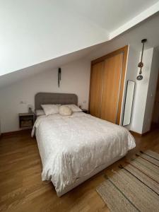 een slaapkamer met een groot bed met een houten vloer bij Apartamento El Picu in Collanzo
