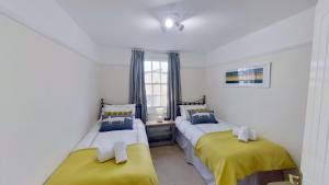 2 camas en una habitación de color amarillo y azul en Bay View, en Sidmouth