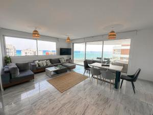 ein Wohnzimmer mit einem Sofa, einem Tisch und Stühlen in der Unterkunft Seaview Pearl Suite Larnaca in Larnaka