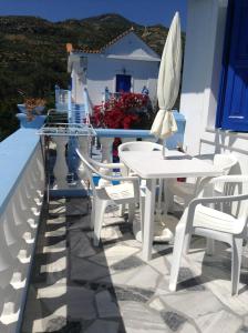 a patio with white tables and chairs and a umbrella at Meltemia Studio Samos No6 Pefkos in Votsalákia