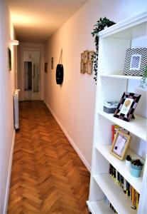 un corridoio con scaffali bianchi e pavimento in legno massello di Casa Vacanze Trieste Piace a Trieste
