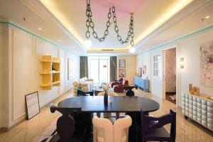 een woonkamer met een tafel en stoelen en een kroonluchter bij Sonar Paraiso: A Dreamy Apartment in Jakarta in Madiun