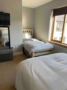 a bedroom with two beds and a flat screen tv at Sea Breeze Cottage Mulranny in Mulranny