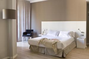a hotel room with a bed, chair, and nightstand at Rambla 102 in Barcelona