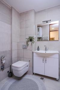 a white bathroom with a toilet and a sink at BLOK apartment in Visoko