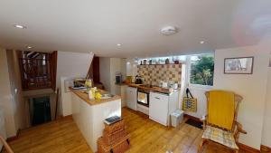 a kitchen with white cabinets and a yellow chair at Otter Barn in Otterton