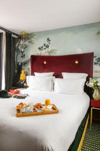 a tray of food sitting on top of a bed at Snob Hotel in Paris