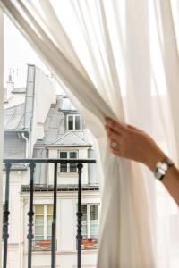 une femme ouvre les rideaux d'une fenêtre dans l'établissement Snob Hotel, à Paris