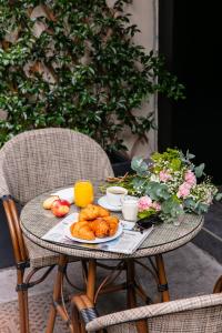 a table with a plate of croissants and fruit on it at Snob Hotel in Paris