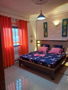 1 dormitorio con 1 cama con cortinas rojas en Chez Roland, en Kribi