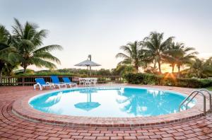 una piscina con sillas, una mesa y palmeras en Sunny Vacation Villa No 98, en San Rafael del Yuma