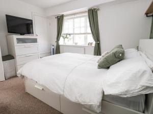 a white bedroom with a bed and a window at 6 Cwrt Griffiths in Rhyl