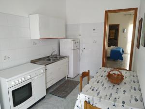 Una cocina blanca con una mesa, un fregadero y un refrigerador. en Vincenzo Apartment, en Lampedusa